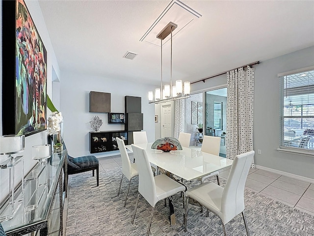 dining space featuring light tile patterned floors, baseboards, visible vents, and a chandelier