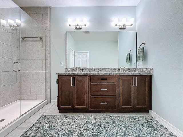 full bathroom with a sink, a stall shower, double vanity, and tile patterned floors