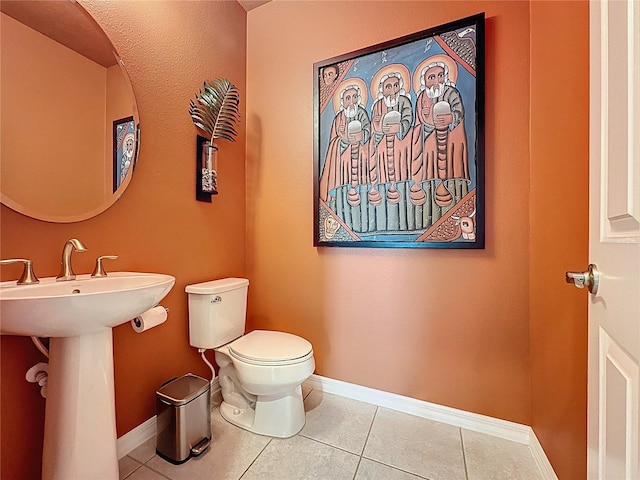 half bathroom featuring tile patterned floors, baseboards, and toilet