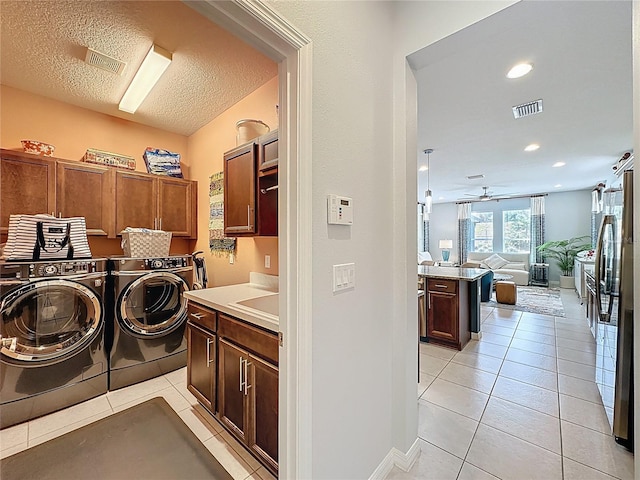 clothes washing area featuring light tile patterned floors, visible vents, cabinet space, and washing machine and clothes dryer