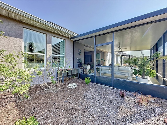 view of side of home with stucco siding and a sunroom