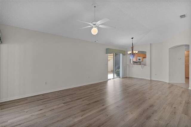 1135 Santa Cruz Dr, The Villages, FL 32162 - spare room featuring visible vents, ceiling fan with notable chandelier, a textured ceiling, arched walkways, and light wood-style floors