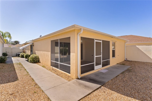 1135 Santa Cruz Dr, The Villages, FL 32162 - back of house with stucco siding, fence, and a sunroom