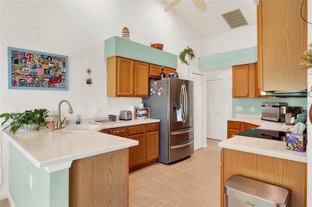 kitchen featuring visible vents, a peninsula, a sink, light countertops, and stainless steel fridge