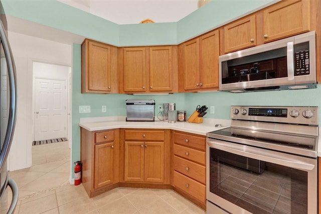 kitchen with light tile patterned floors, stainless steel appliances, and light countertops