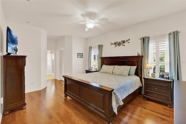 bedroom featuring a ceiling fan, light wood-style floors, baseboards, and ensuite bathroom