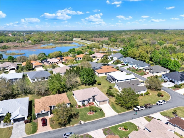 drone / aerial view with a view of trees, a water view, and a residential view