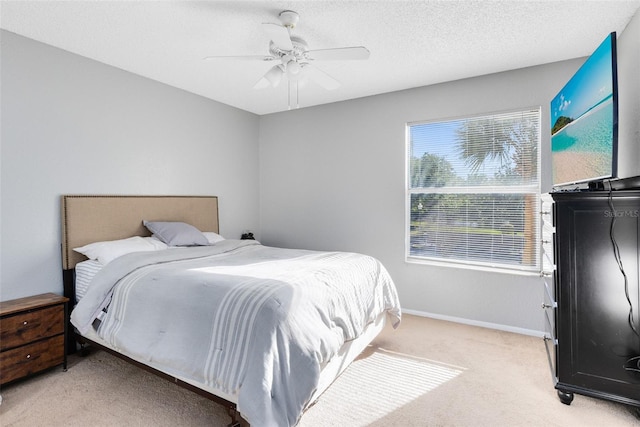 bedroom featuring a ceiling fan, light colored carpet, baseboards, and a textured ceiling