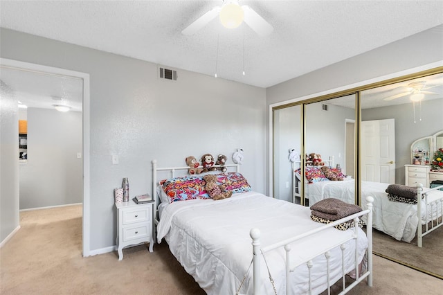 bedroom featuring a ceiling fan, visible vents, a closet, a textured ceiling, and light carpet