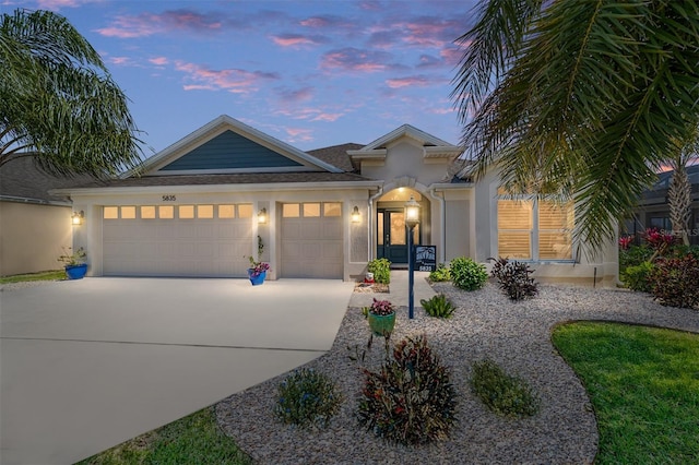 view of front facade featuring concrete driveway, an attached garage, and stucco siding