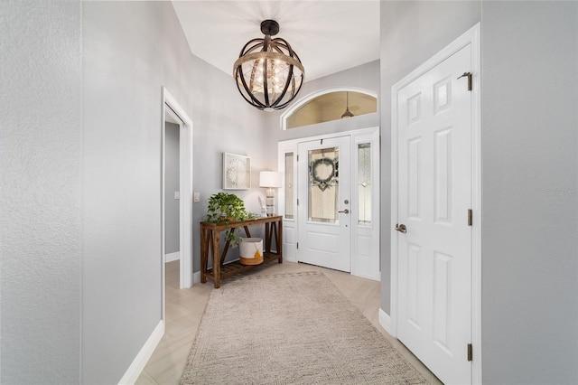 entryway featuring baseboards and a chandelier