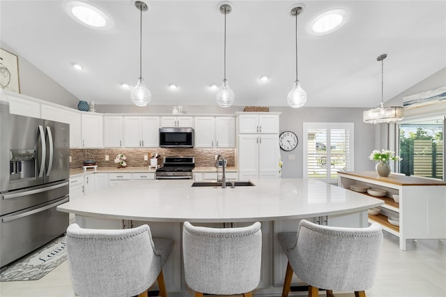 kitchen with a sink, decorative backsplash, vaulted ceiling, light countertops, and appliances with stainless steel finishes