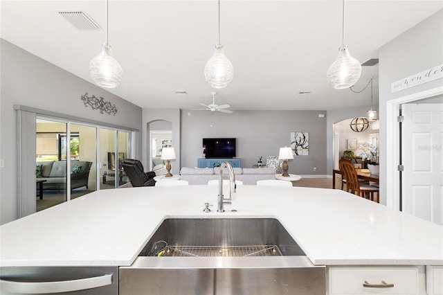 kitchen with visible vents, open floor plan, light countertops, arched walkways, and a sink