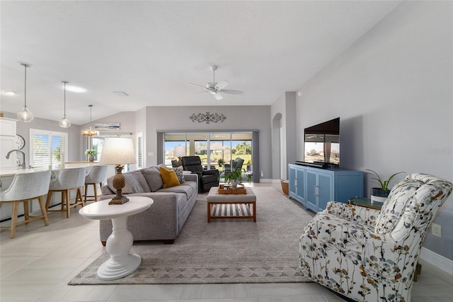 living room with arched walkways, ceiling fan, baseboards, and lofted ceiling