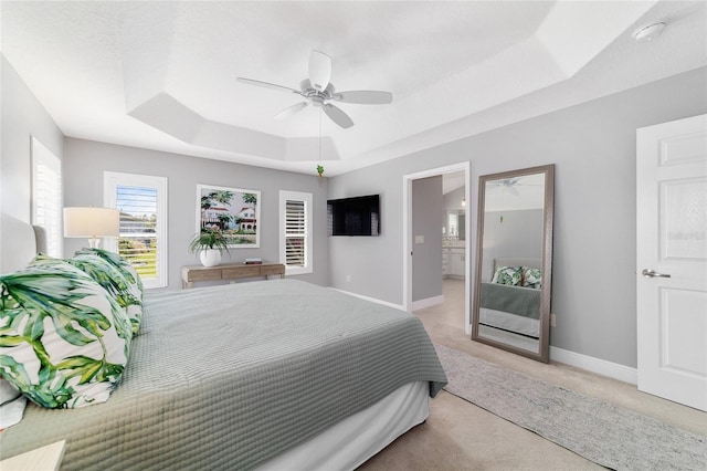 bedroom featuring light colored carpet, a ceiling fan, a raised ceiling, and baseboards