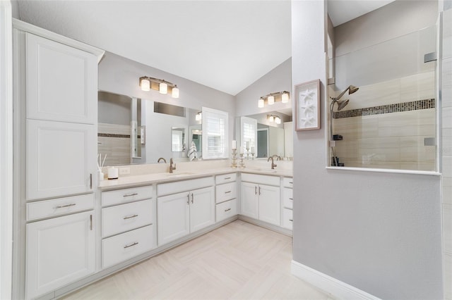 full bath featuring a tile shower, vaulted ceiling, double vanity, and a sink