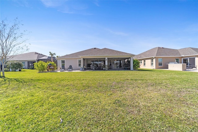 rear view of property featuring stucco siding, a sunroom, a lawn, and a patio area