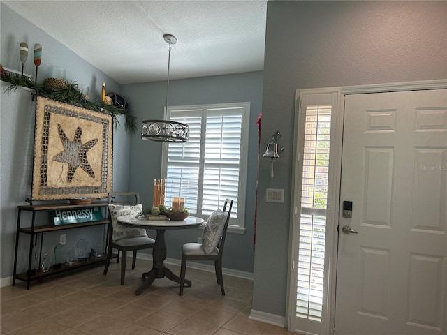 dining room featuring tile patterned floors, baseboards, and a textured ceiling