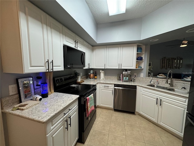 kitchen featuring light tile patterned floors, white cabinets, black appliances, and a sink