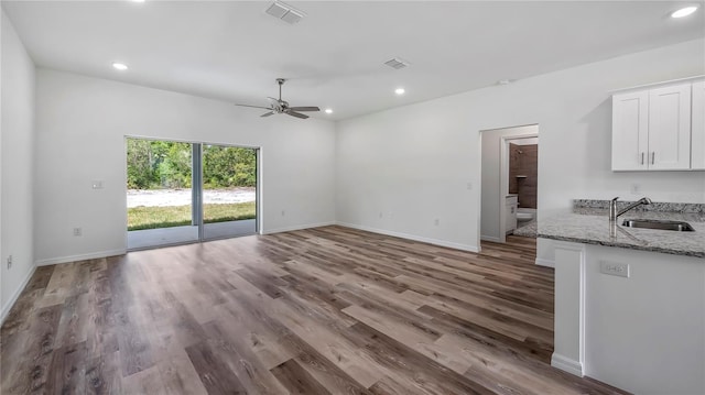 unfurnished living room with visible vents, a sink, wood finished floors, recessed lighting, and baseboards