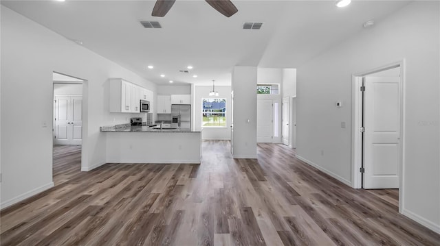 kitchen with wood finished floors, visible vents, a peninsula, appliances with stainless steel finishes, and white cabinetry