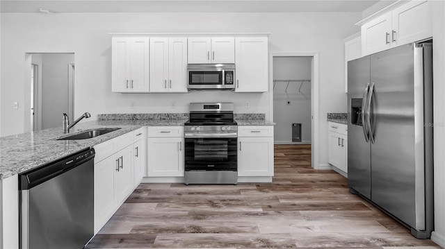 kitchen with white cabinets, a peninsula, stainless steel appliances, and a sink