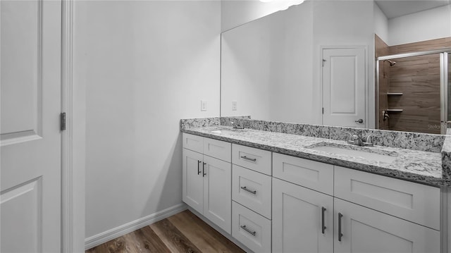 bathroom featuring double vanity, wood finished floors, baseboards, and a sink