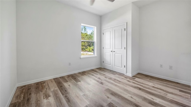 unfurnished bedroom with a closet, ceiling fan, baseboards, and wood finished floors