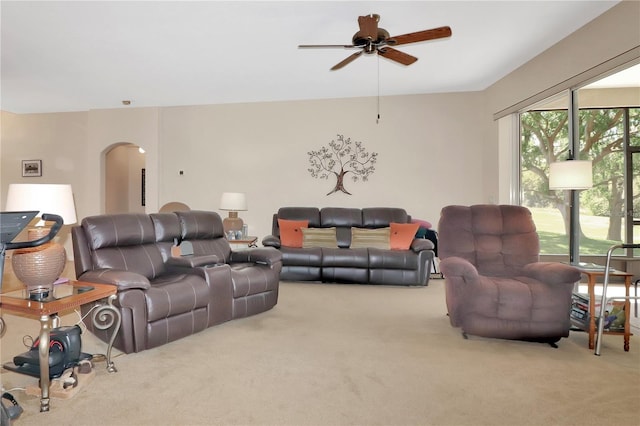 carpeted living area featuring arched walkways and ceiling fan