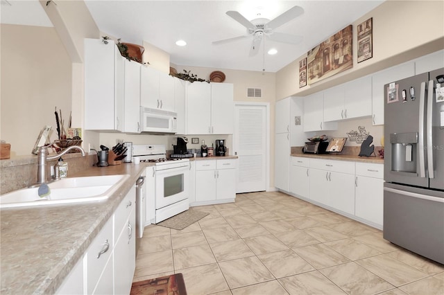 kitchen featuring visible vents, a sink, white appliances, light countertops, and ceiling fan