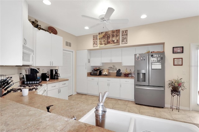 kitchen with white microwave, visible vents, light countertops, stove, and stainless steel fridge