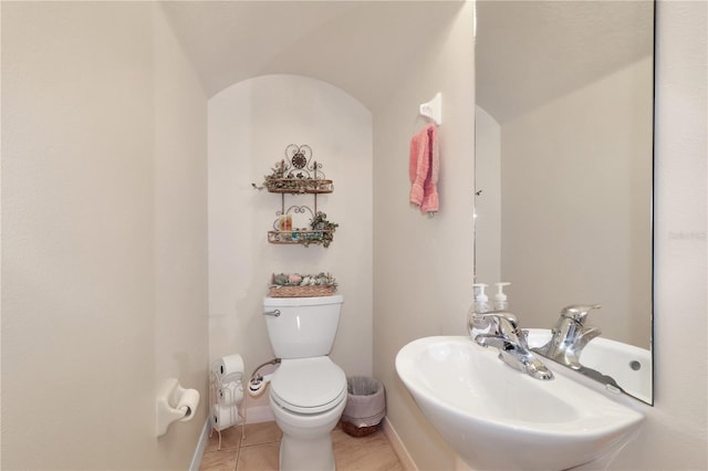 bathroom featuring a sink, baseboards, toilet, and tile patterned flooring