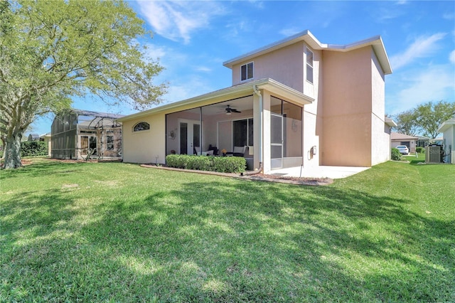 rear view of house featuring stucco siding, a lawn, a lanai, and ceiling fan