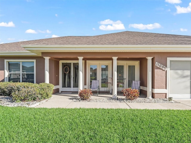 entrance to property with roof with shingles, stucco siding, french doors, a garage, and a yard