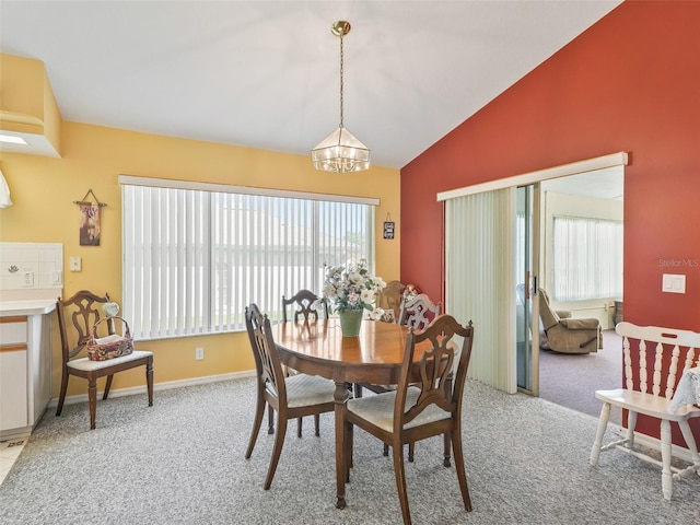 dining area with baseboards, light colored carpet, a chandelier, and vaulted ceiling