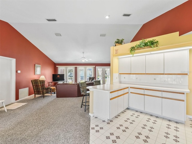 kitchen featuring visible vents, light colored carpet, a peninsula, and light countertops