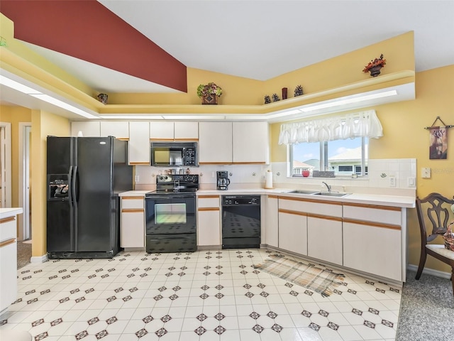 kitchen with black appliances, light countertops, lofted ceiling, and a sink