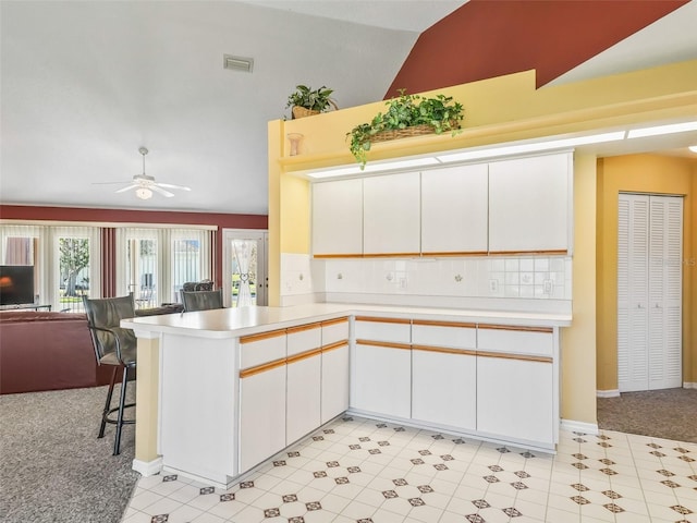 kitchen with a ceiling fan, open floor plan, a peninsula, light countertops, and lofted ceiling