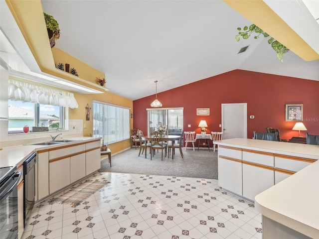 kitchen with light countertops, lofted ceiling, hanging light fixtures, black appliances, and a sink