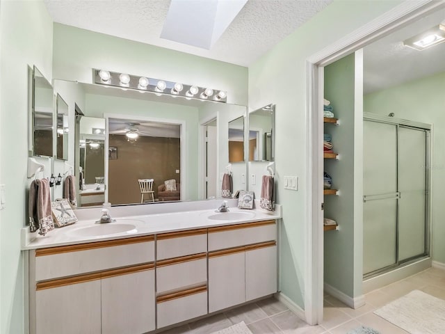 bathroom with double vanity, a shower stall, a textured ceiling, and a sink