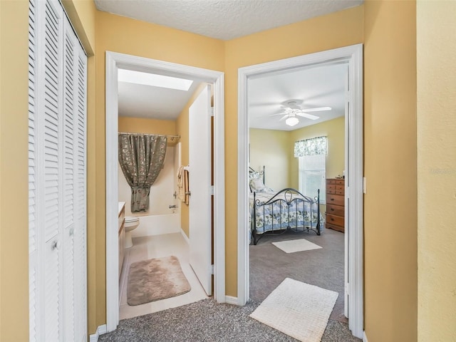 hallway featuring baseboards, a textured ceiling, and carpet flooring