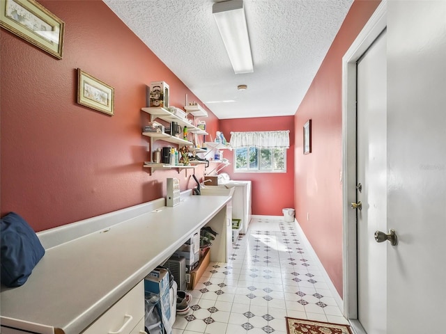 laundry area with light tile patterned floors, a textured ceiling, and baseboards