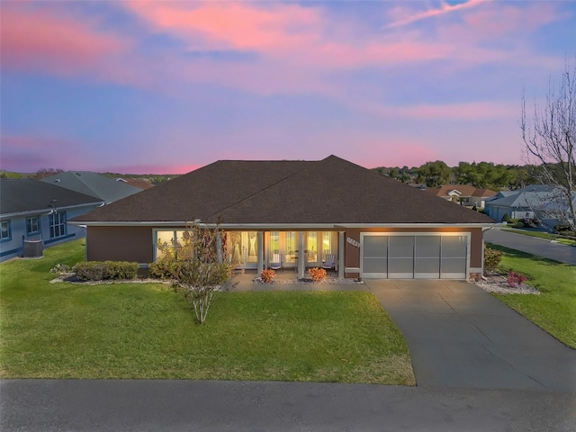 ranch-style house with a garage, concrete driveway, central AC, and a front lawn