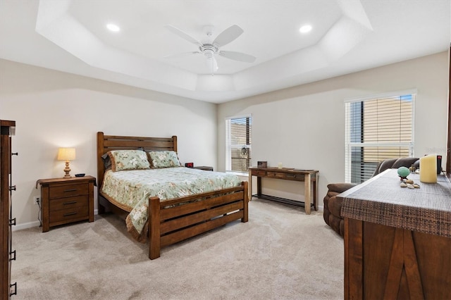 bedroom featuring light carpet, a raised ceiling, a ceiling fan, recessed lighting, and baseboards