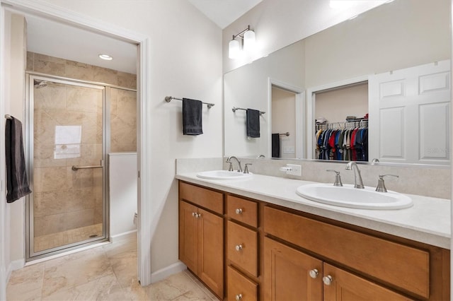 bathroom featuring double vanity, a stall shower, a spacious closet, and a sink