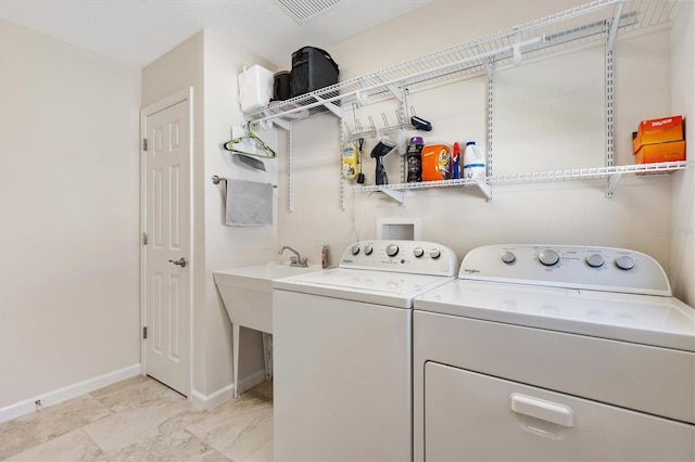 clothes washing area featuring laundry area, separate washer and dryer, and baseboards