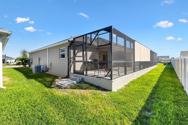 rear view of property featuring a lanai, central air condition unit, a yard, and fence