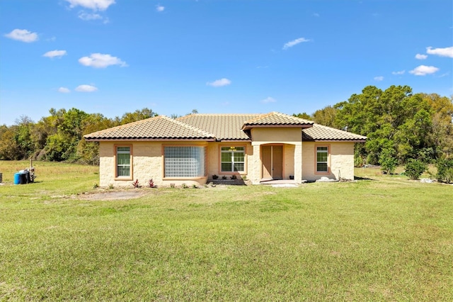 rear view of property with a yard, stucco siding, and a tile roof