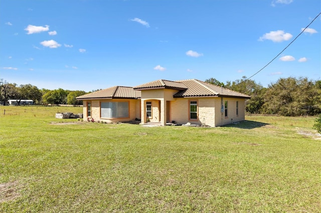 back of property featuring a yard, stucco siding, and a tiled roof