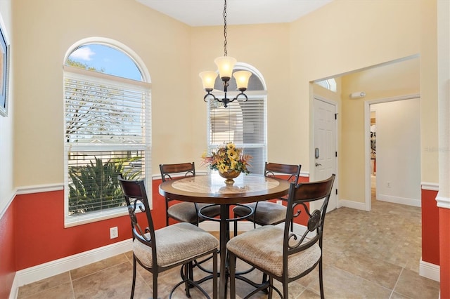 dining space with light tile patterned floors, a notable chandelier, a high ceiling, and baseboards